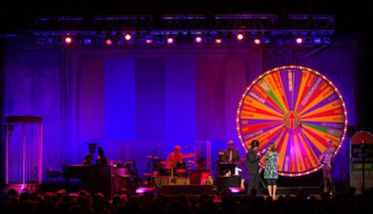 A fan onstage spins the wheel for Elvis Costello's next song.